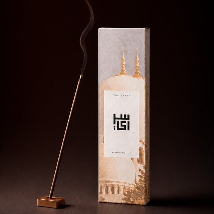 Oud Fakhama incense sticks box beside a burning oud stick in a holder